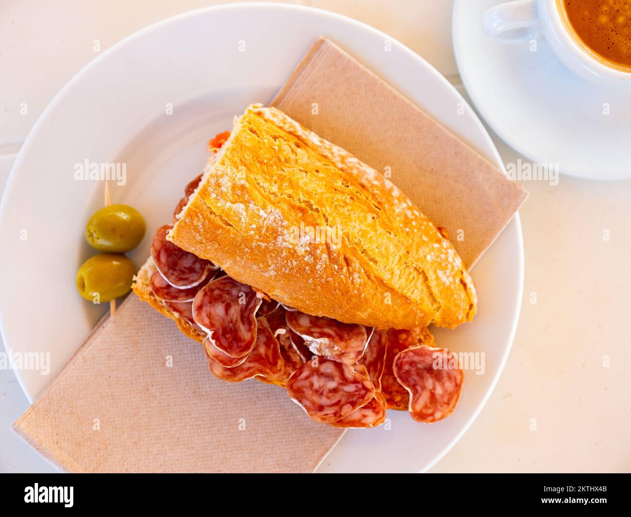 Spanisches Frühstück: Geräuchertes Würstchen-Fuet-Sandwich und Oliven in der Nähe Stockfoto