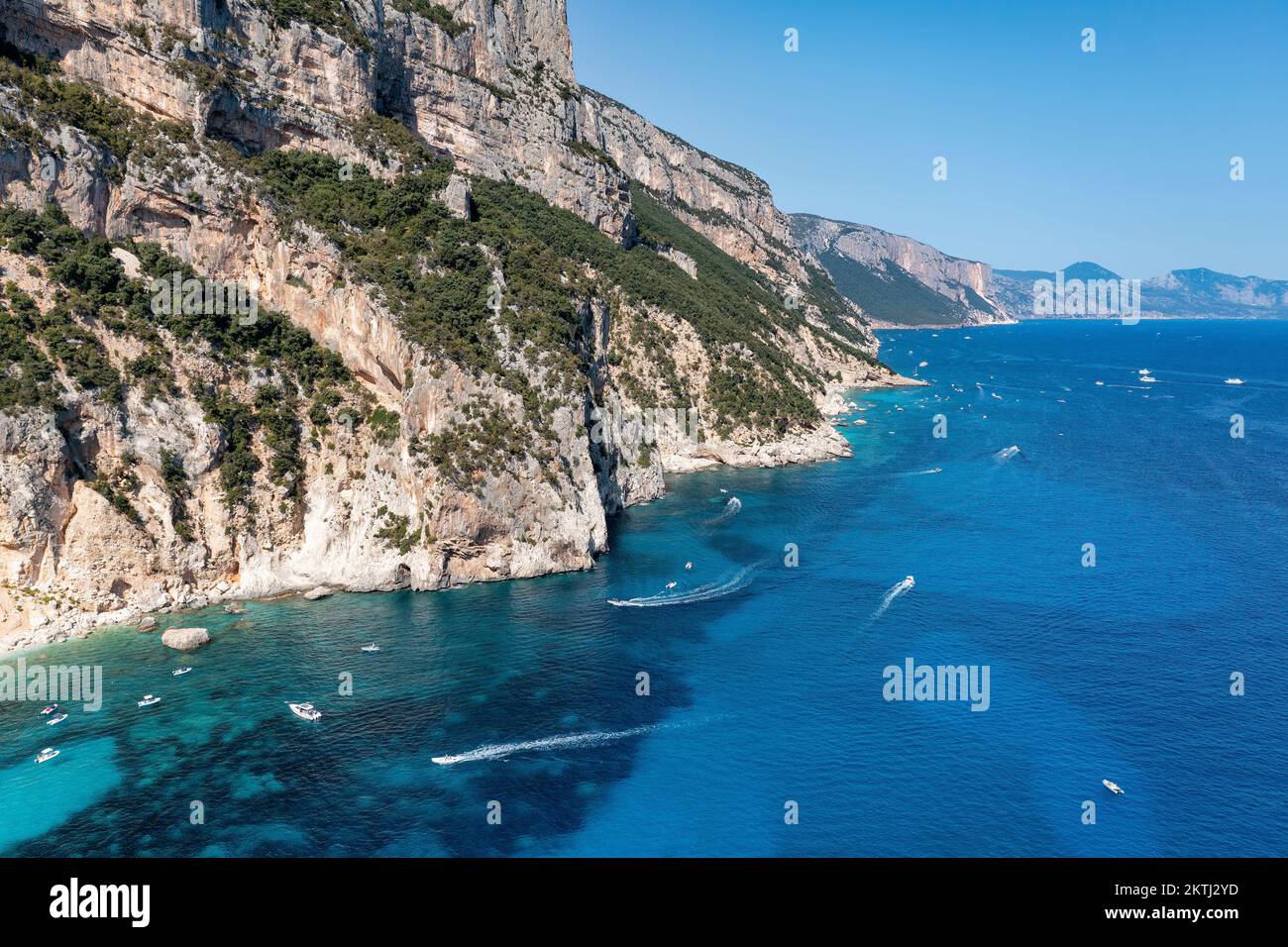 Die Touristenboote entlang der zerklüfteten, von Klippen gesäumten Küste Ostsardiniens im Golfo di Orosei in der Nähe der malerischen Küstenstadt Cala Gonone aus der Vogelperspektive. Stockfoto