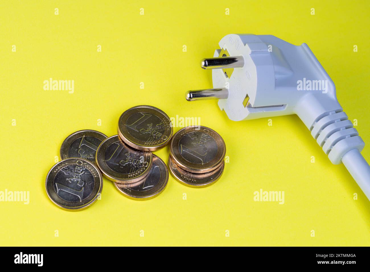 schuko-Stecker und Euro-Münzen auf gelbem Hintergrund Stockfoto