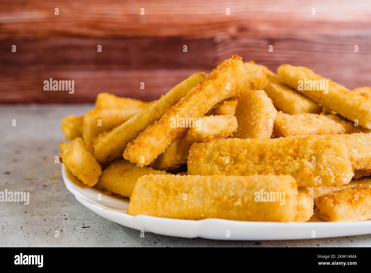 Fisch klebt in knuspriger goldener Panade, Nahaufnahme auf weißem Teller auf dem Küchentisch, selektiver Fokus Stockfoto