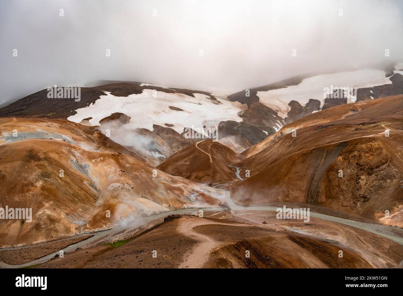 Brücke und dampfende Bäche zwischen farbenfrohen Rhyolitenbergen und Schneefeldern, geothermisches Gebiet Hveradalir, Kerlingarfjöll, isländische Highlands, Icel Stockfoto