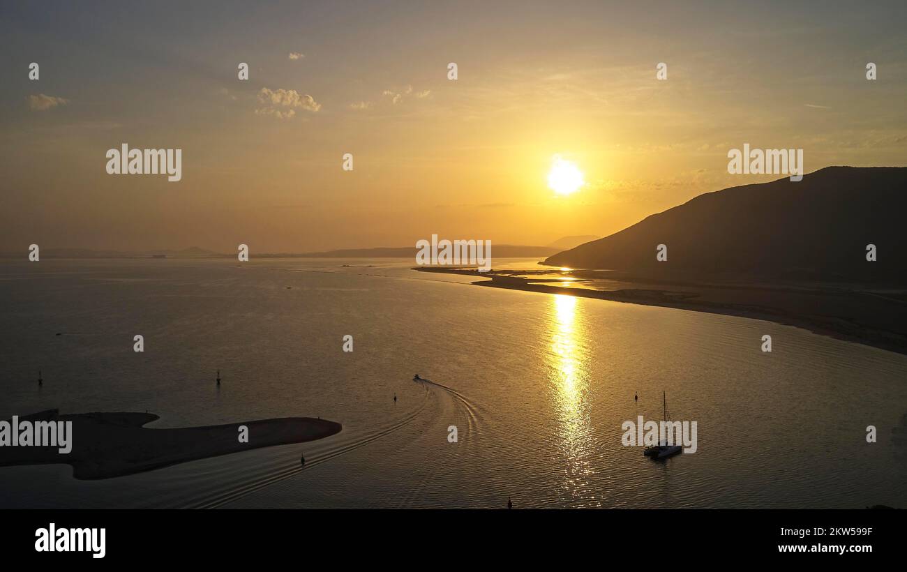 Drohnenschuss, Sonnenaufgang, Sonnenreflexionen auf dem Meer, Katamaran, Hafeneingang, Boot, Hügel, Lefkada Stadt, Hauptstadt, Lefkada Insel, Lefkas, Ionische Insel Stockfoto