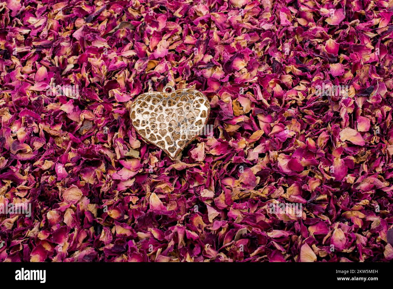 Goldene Farbe Herz auf trockenen Rosenblüten Hintergrund Stockfoto