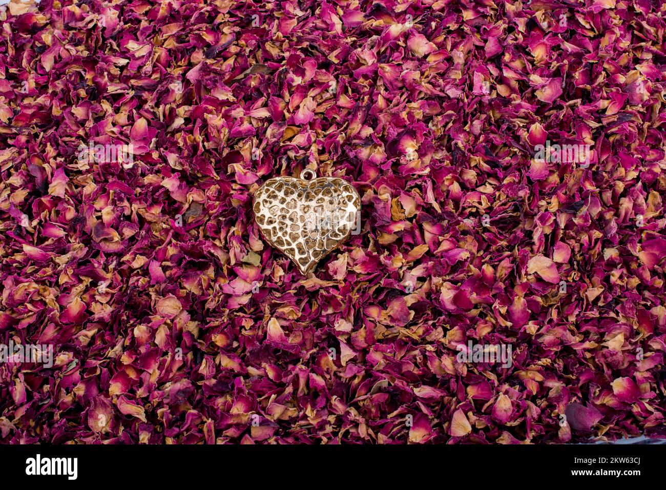 Goldene Farbe Herz auf trockenen Rosenblüten Hintergrund Stockfoto