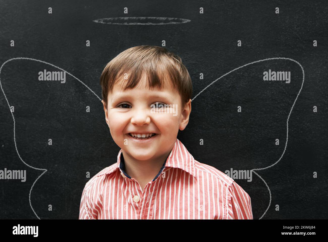 Zeichnen macht so viel Spaß. Studioaufnahme eines entzückenden kleinen Jungen mit Kreidezeichnungen hinter ihm. Stockfoto