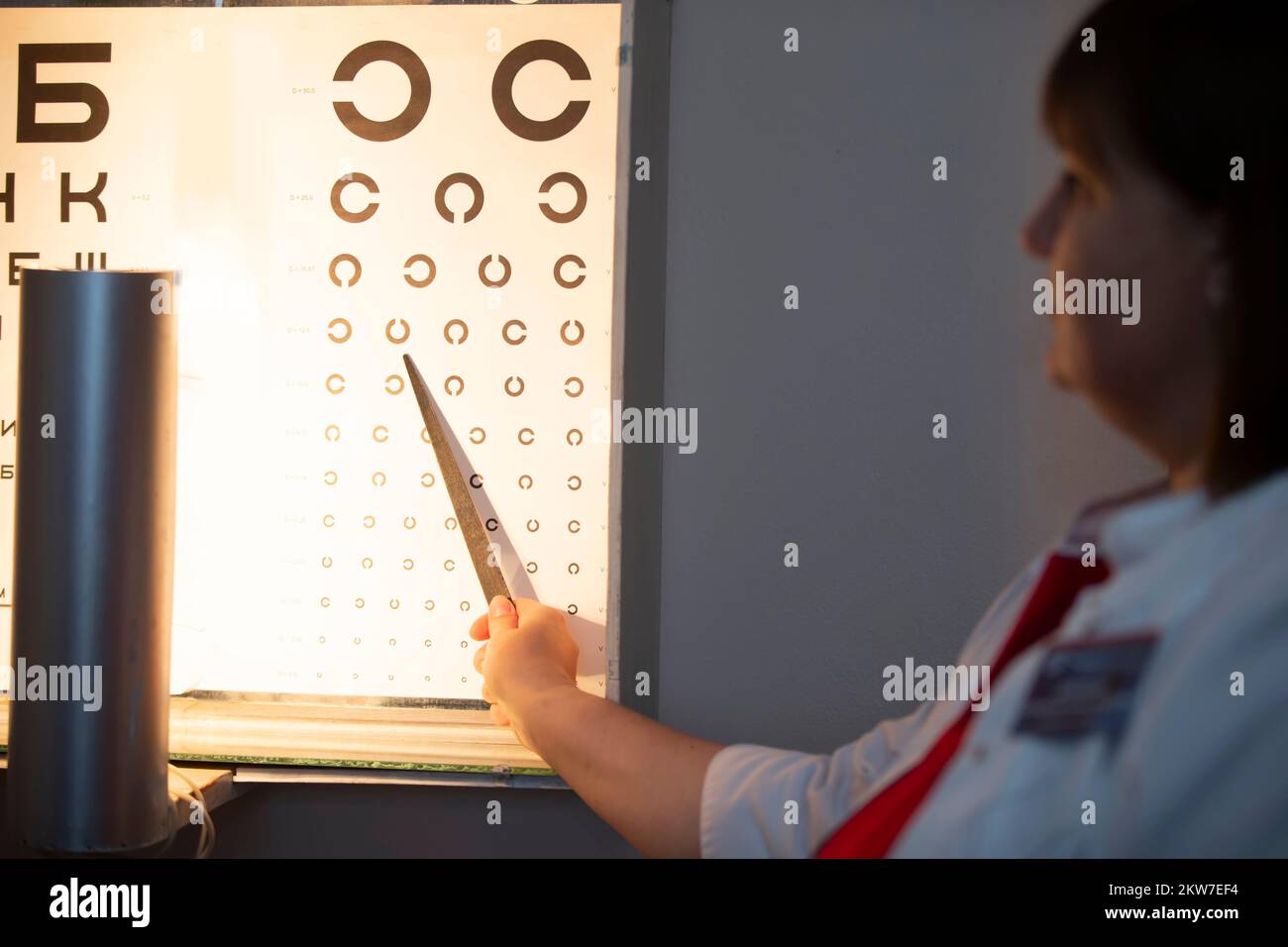 Arzt mit einem Zeiger, eine Augenkarte, mit der die Sehschärfe gemessen werden kann. Das Konzept der Sehkorrektur Stockfoto