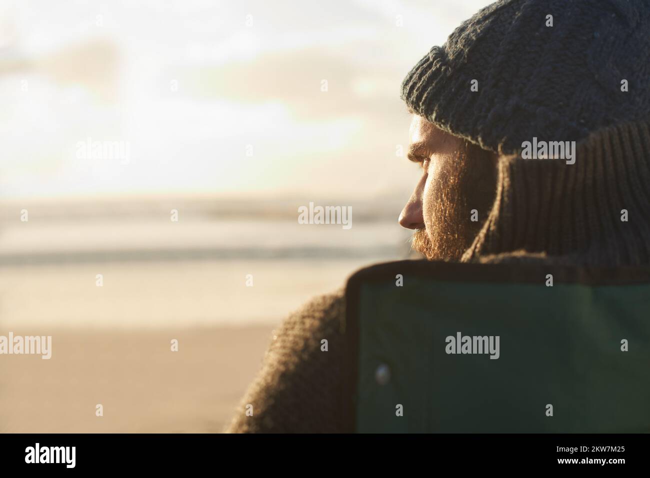 Meerblick. Über der Schulter sieht man einen Mann, der am Strand sitzt. Stockfoto