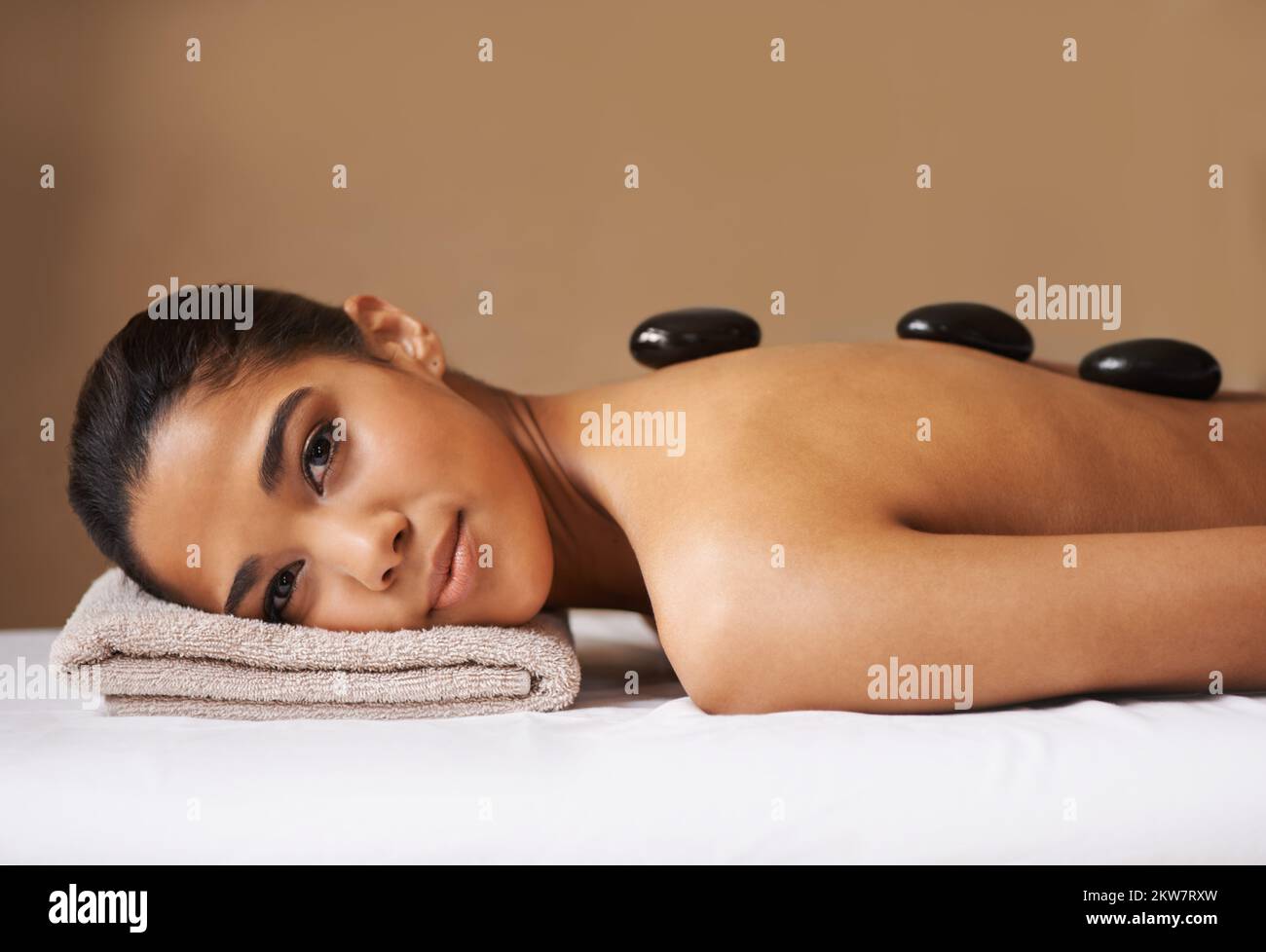 Hot Stone Entspannung. Eine junge ethnische Frau, die in einem Spa eine Behandlung mit heißen Steinen erhält. Stockfoto