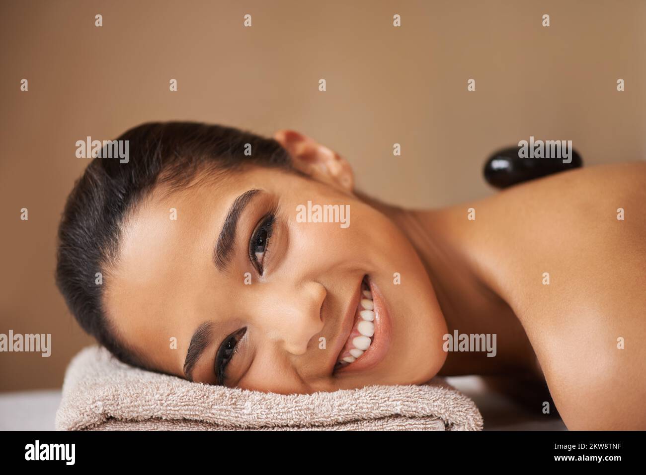 Hot Stone Entspannung. Eine junge ethnische Frau, die in einem Spa eine Behandlung mit heißen Steinen erhält. Stockfoto