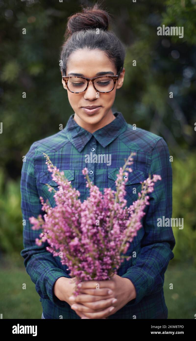 Frische Blumen für zu Hause. Eine junge Frau, die einen Blumenstrauß in einem Garten hält. Stockfoto