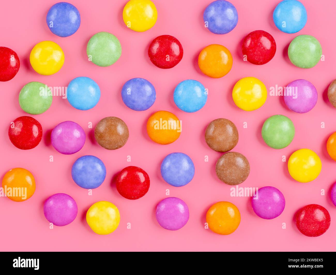 Bunte, zuckerbeschichtete Süßschokolade auf pinkfarbenem Hintergrund Stockfoto