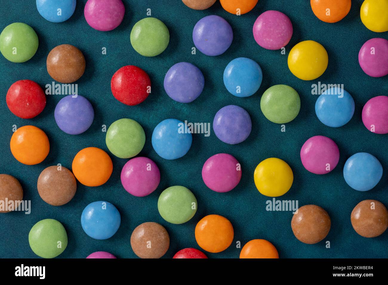 Mehrfarbige zuckerbeschichtete Schokoladenbonbons auf dunkelgrünem Hintergrund Stockfoto