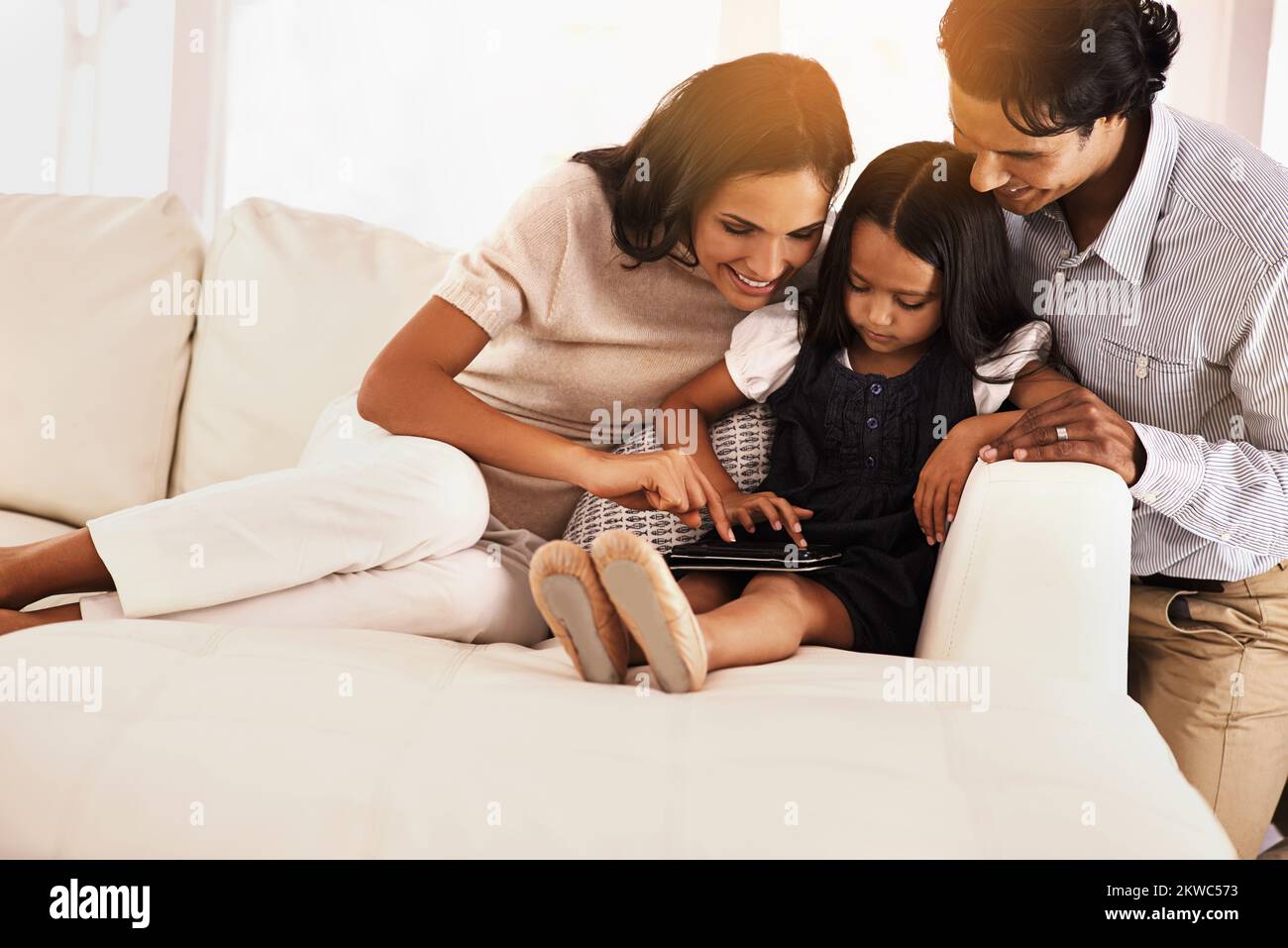 Zeig uns, was du tust... ein Bild einer liebevollen jungen Familie, die sich ein digitales Tablet teilt. Stockfoto