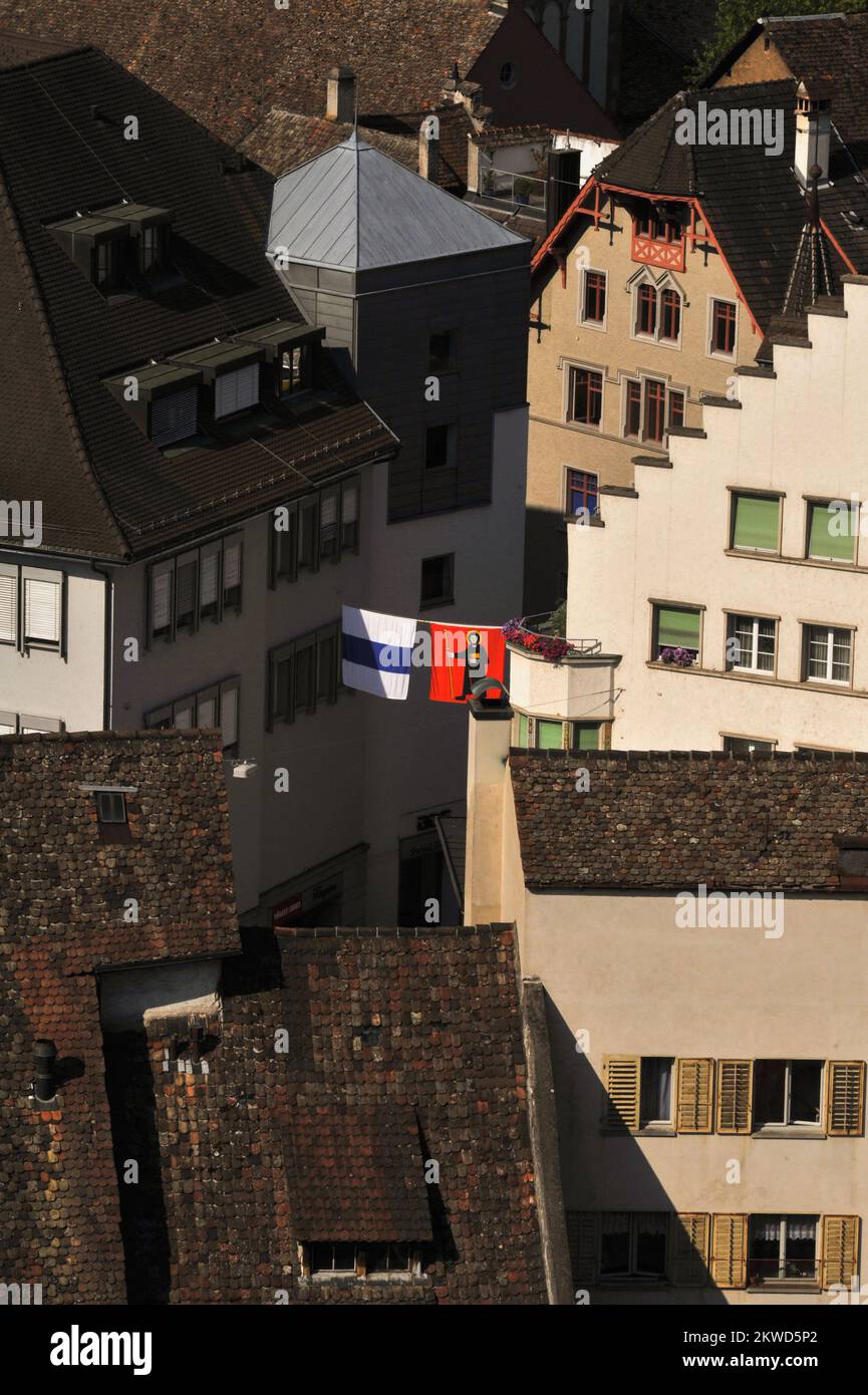 Bunt gefärbte Flaggen oder Banner mit den Waffen und Emblemen der Schweizer Kantone hängen in den verkehrsfreien Straßen der Altstadt oder der Altstadt von Schaffhausen neben dem Hochrhein in der Nordschweiz. Die antike Stadt beherbergt viele feine Gotik-, Renaissance- und Barock-Gilden- oder Handelshäuser mit orielen Fenstern und Fassaden mit Fresken. Stockfoto