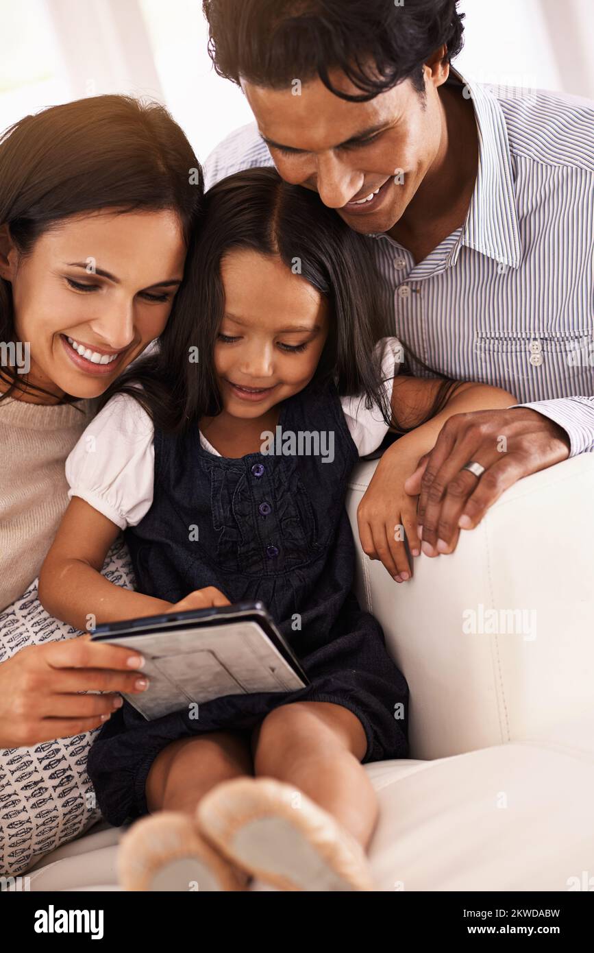 Ihre Eltern zu erziehen. Eine liebevolle junge Familie, die sich ein digitales Tablet teilt. Stockfoto