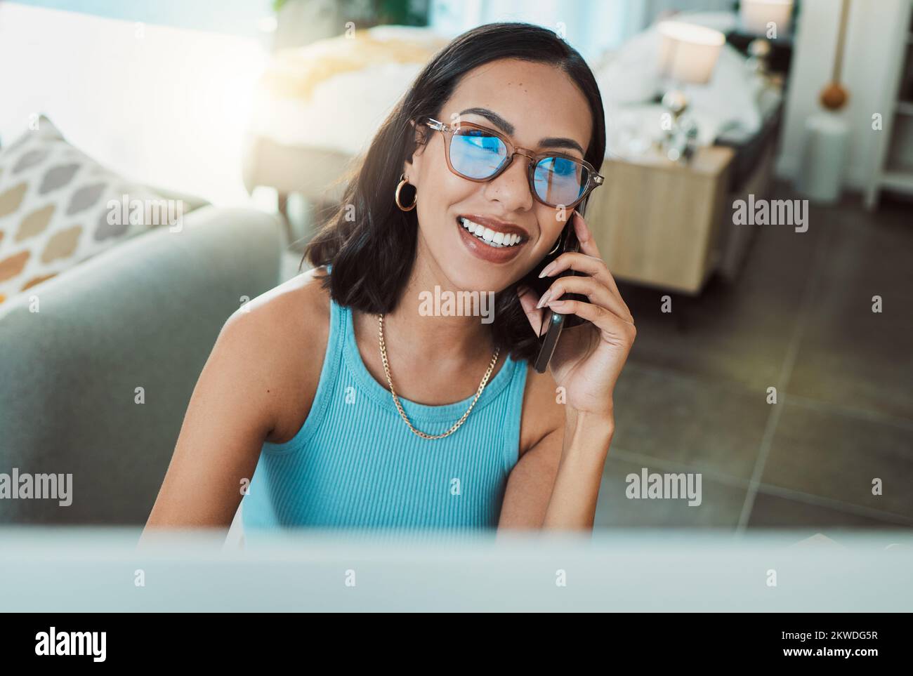 Arbeiten von einem Freiberufler zu Hause aus, der telefoniert, während er Remote-Arbeit am Computer erledigt. Lächelnde, glückliche und motivierte Frau, die denkt, berät und Stockfoto