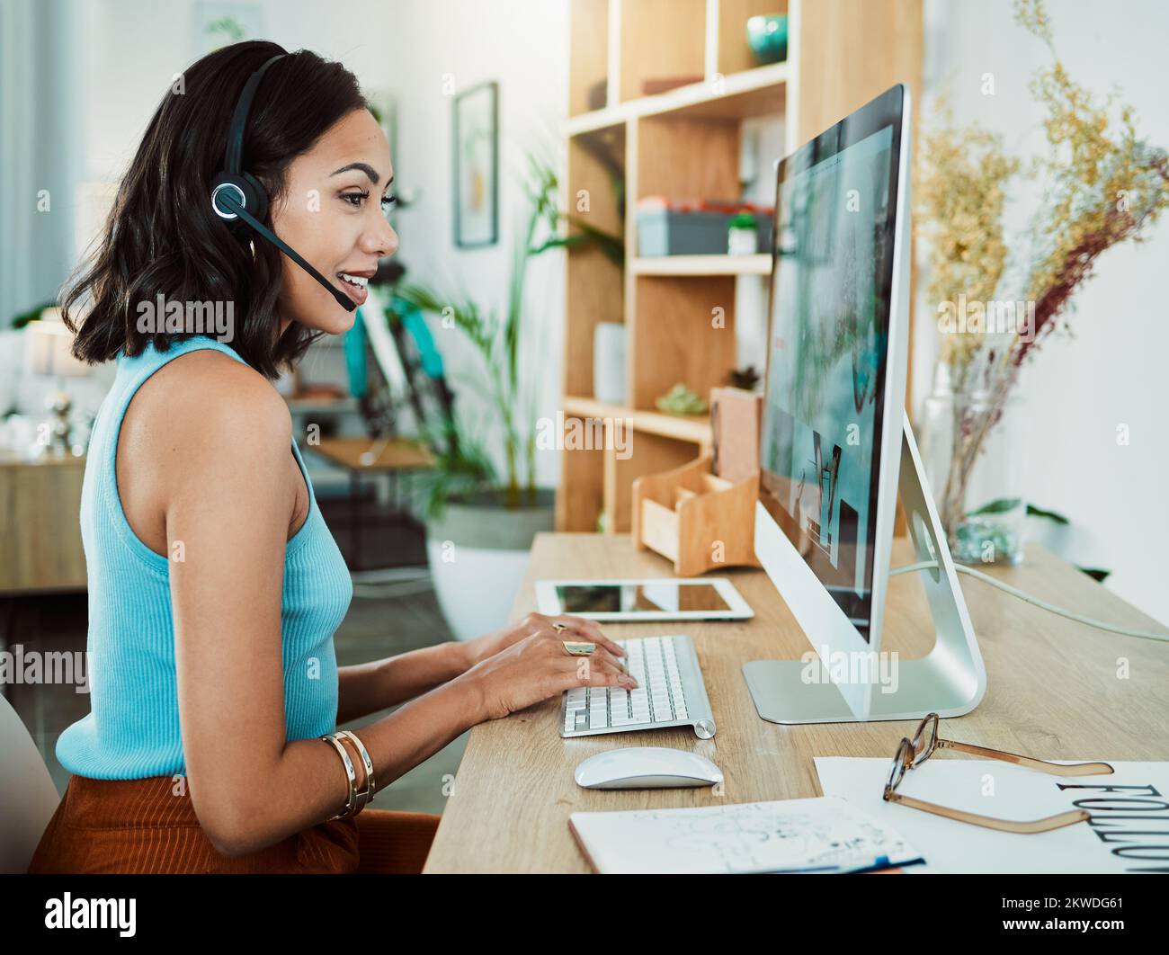Arbeiten, Tippen und Telefonieren eines Kundendienstmitarbeiters online, um einem Kunden am Computer zu helfen. Weibliche Web-Mitarbeiter helfen Mitarbeitern im digitalen Callcenter mit Stockfoto