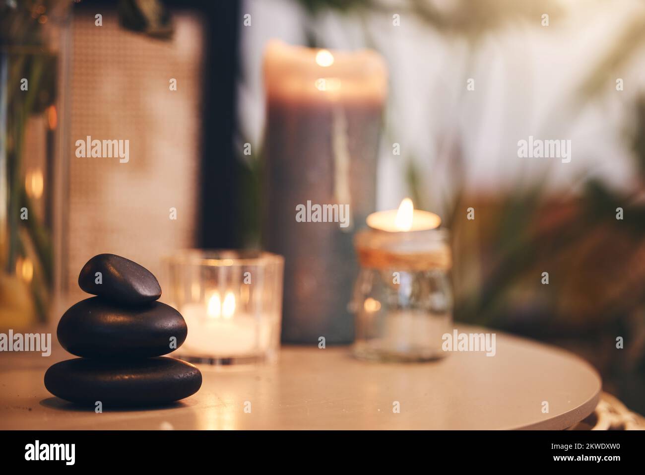 Stein, Kerze und Spa mit stillen Gegenständen auf einem Tisch in einem Wellnesscenter für Aromatherapie zum Entspannen. Hintergrund, Fels und Luxus mit Steinen und Stockfoto