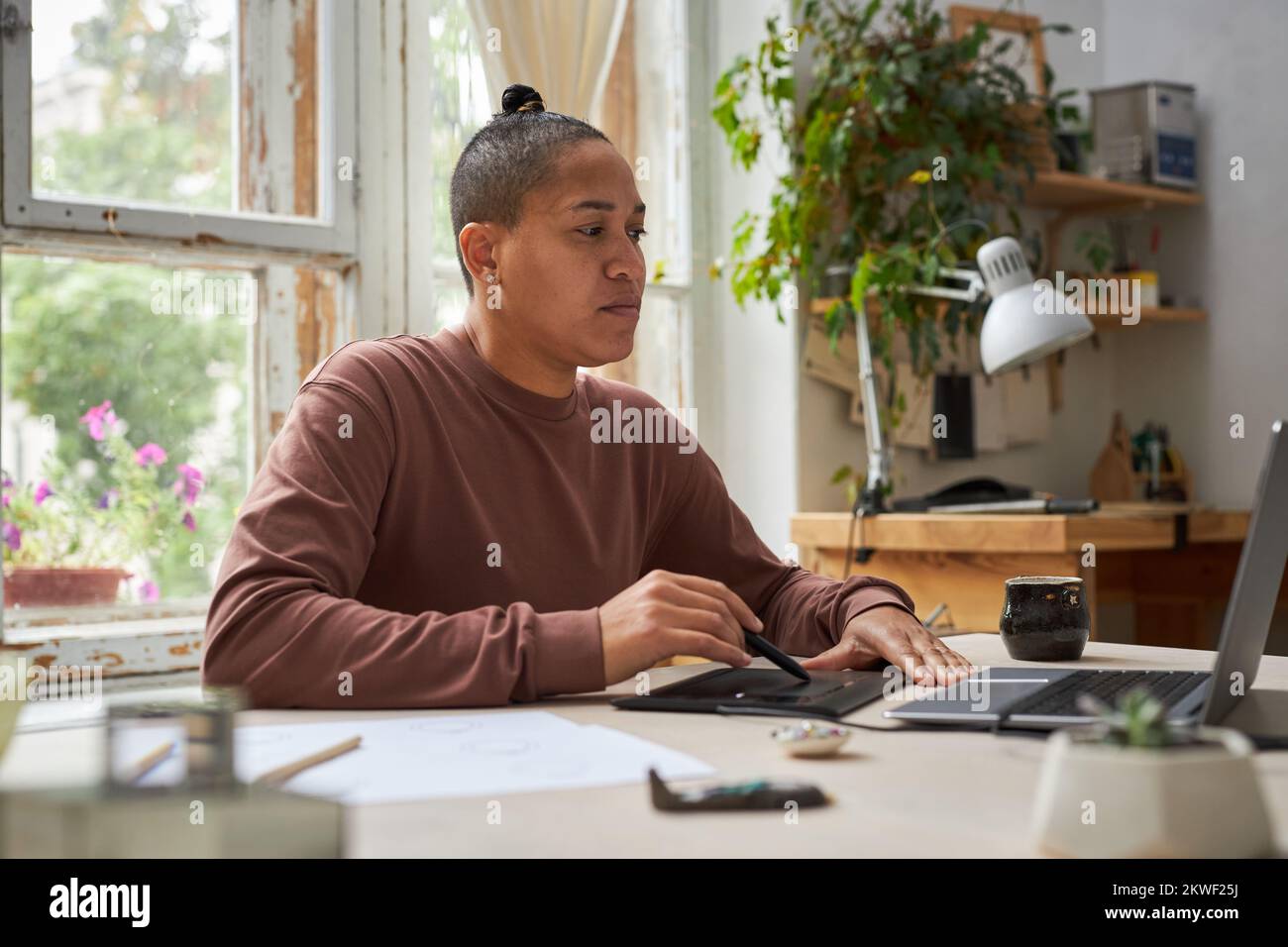 Seitliches Porträt einer Künstlerin mit Grafiktablett und Notebook im Kreativstudio Stockfoto
