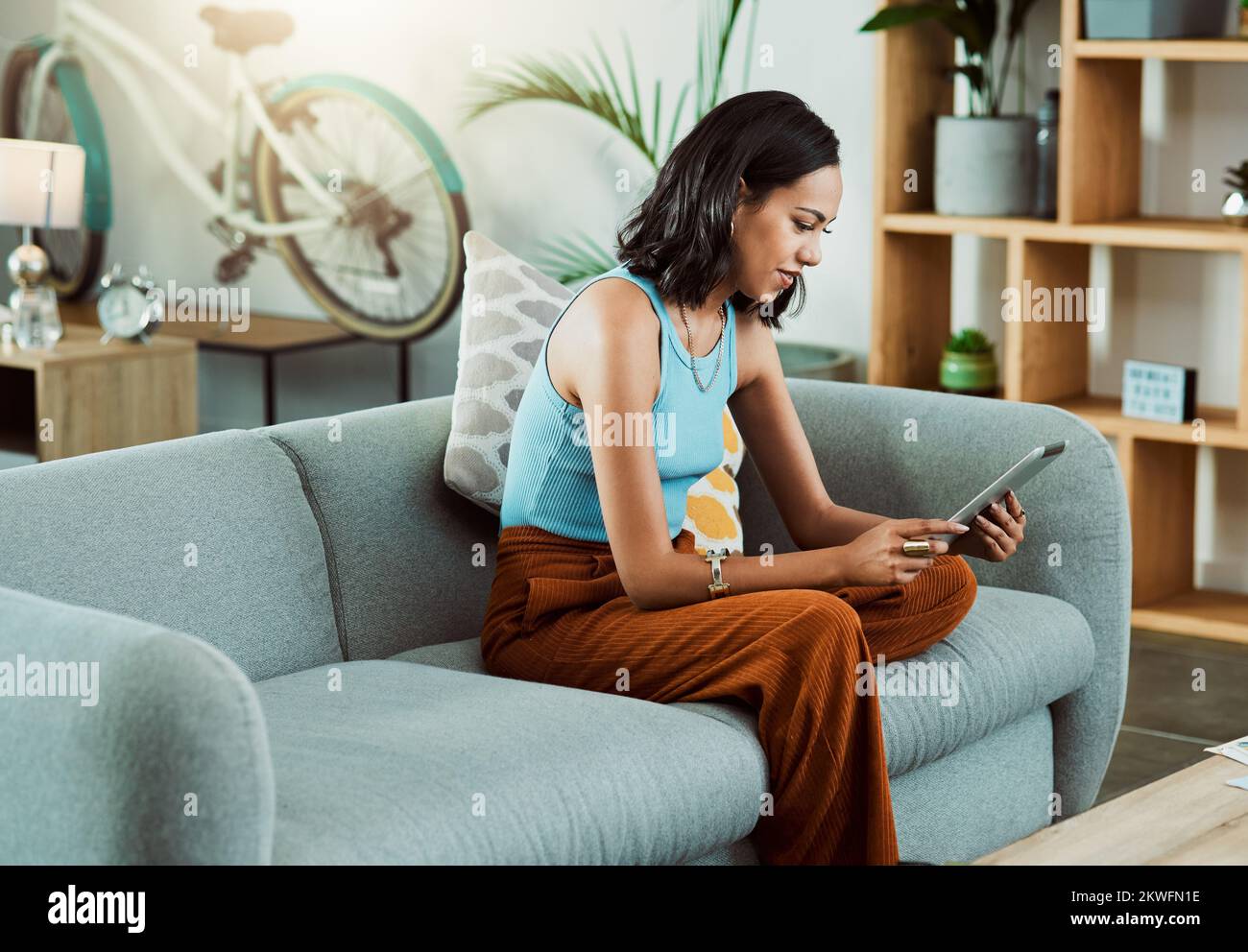 Sie können auf einem Tablet nach Spielfilmen suchen, Videos streamen und in sozialen Medien scrollen, während Sie sich allein auf dem Sofa zu Hause entspannen. Stilvoll Stockfoto