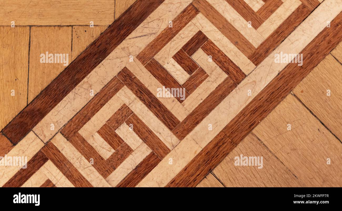Altmodisches Parkett aus verschiedenen Holzplanken mit geometrischen Verzierungen, bekannt als der griechische Schlüssel oder Meander. Fotostruktur des Hintergrunds, Draufsicht Stockfoto