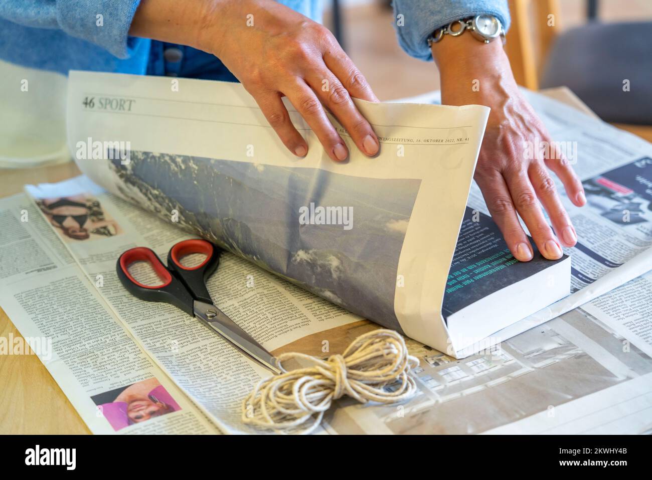 Nachhaltige Geschenkverpackung, in Zeitungen, ohne Klebeband, nur mit Kabel gebunden, Stockfoto