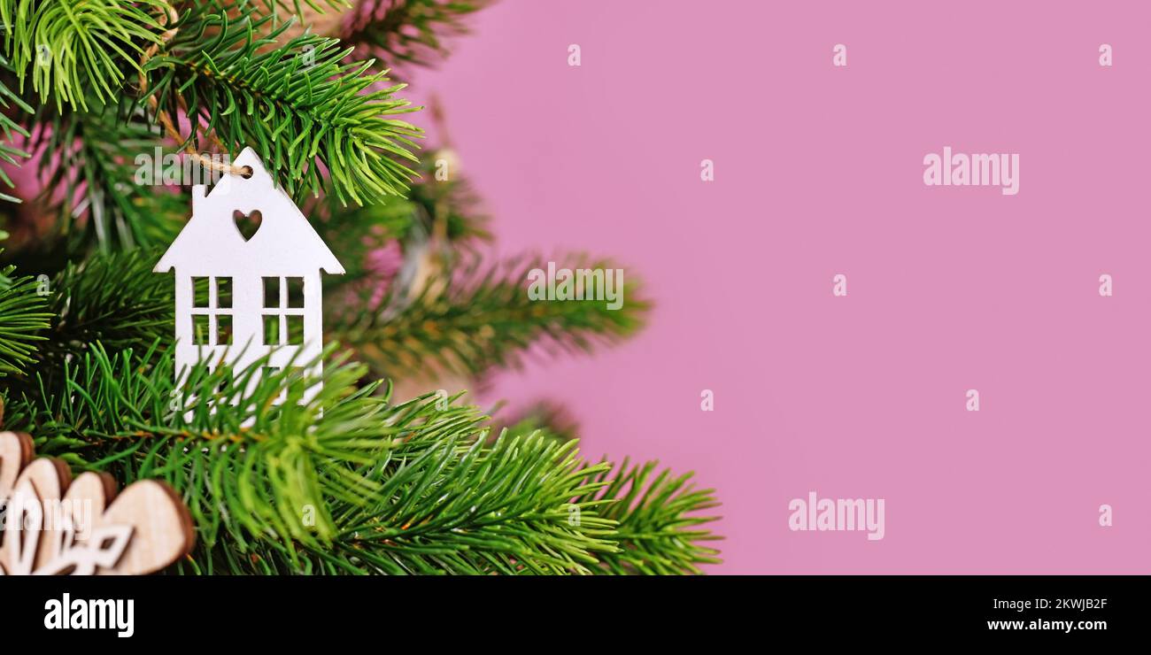 Banner mit Weihnachtsbaum, dekoriert mit weißen, hausförmigen Weihnachtsbaumkugeln auf pinkfarbenem Hintergrund und leerem Kopierfeld Stockfoto