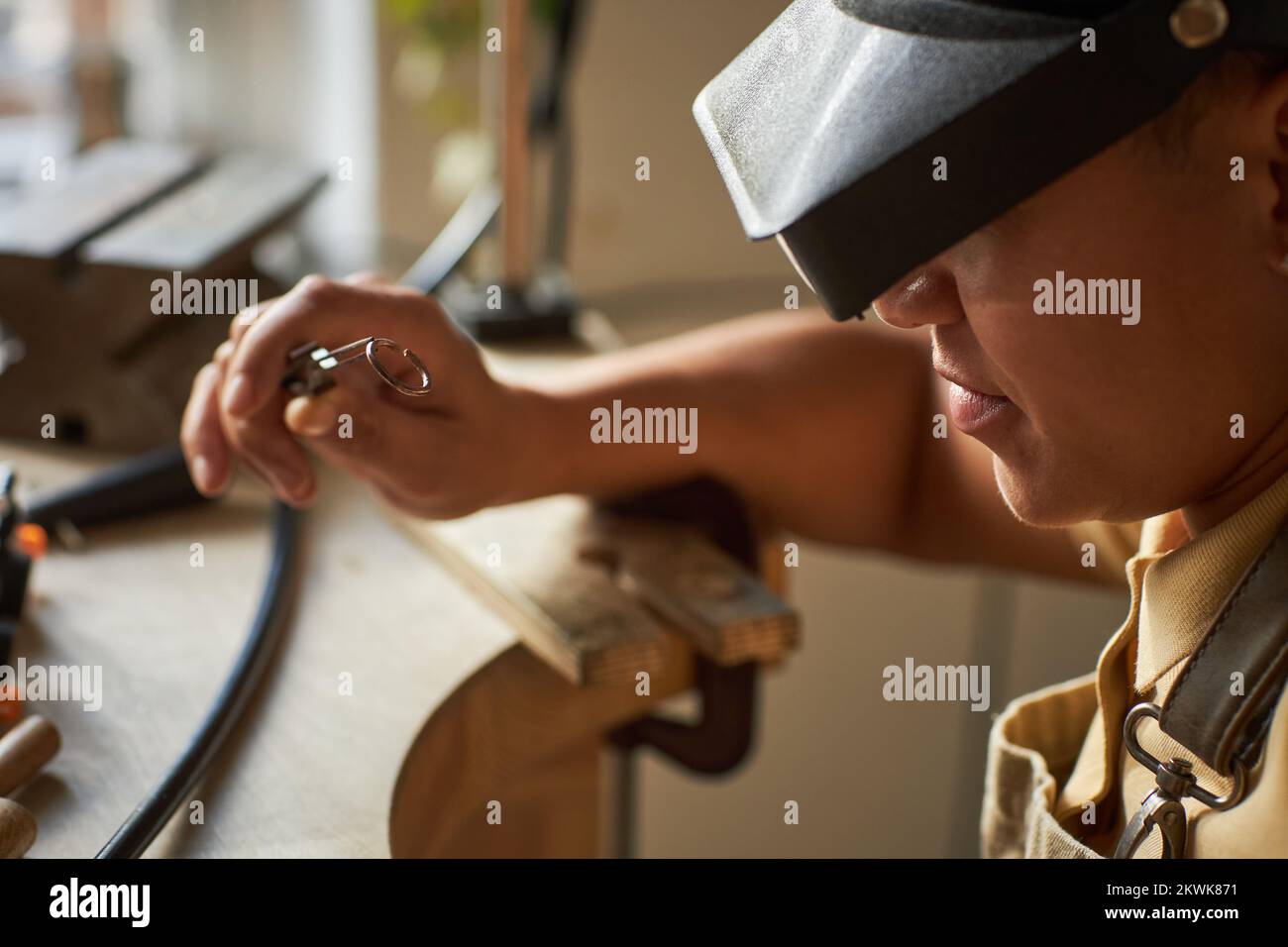 Nahaufnahme einer Juwelierin in Seitenansicht, die beim Erstellen eines Kunststücks eine Lupenbrille trägt Stockfoto