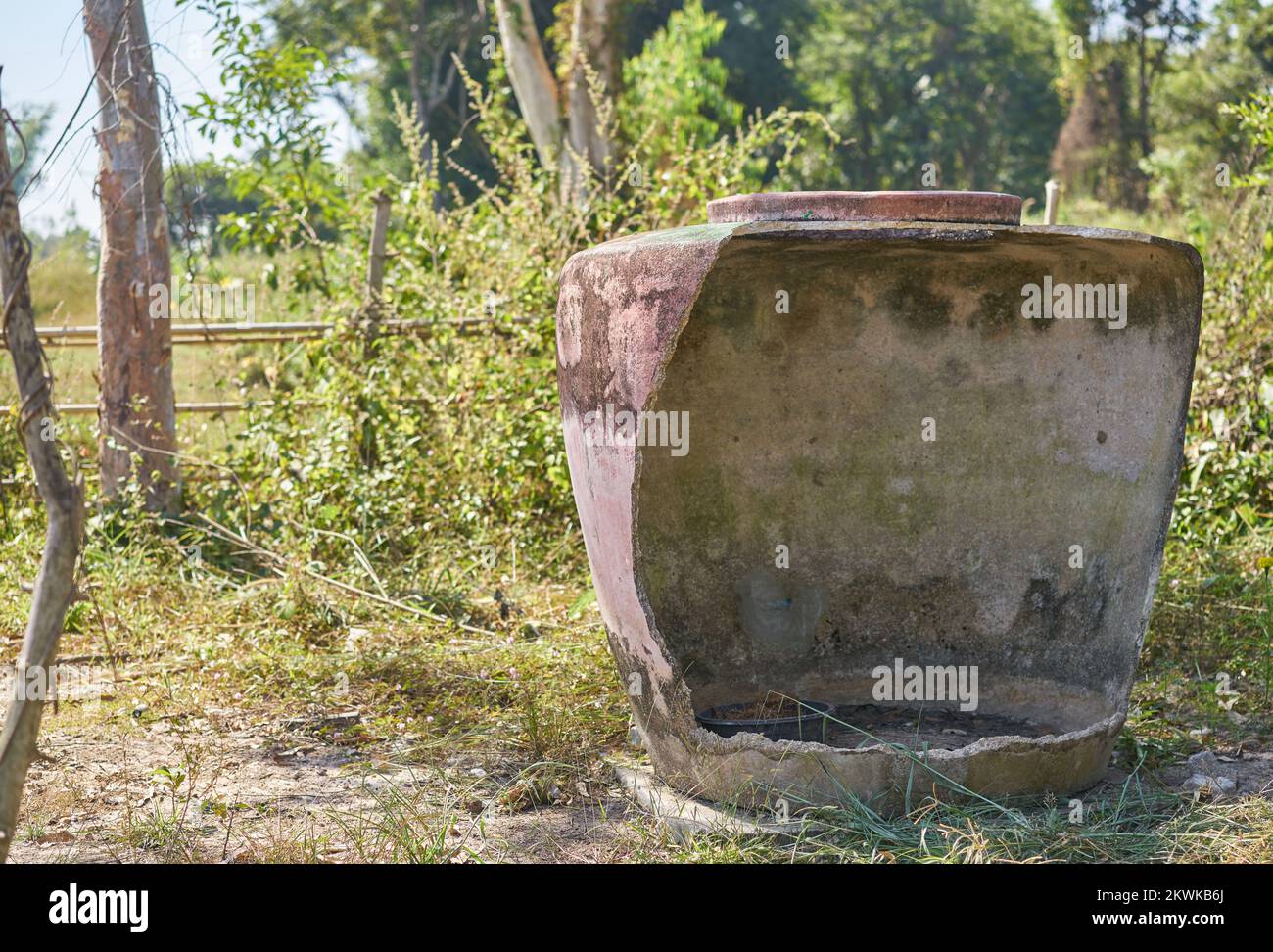 Ein großer traditioneller beschädigter Wasserbehälter auf einer Farm im ländlichen Thailand. Stockfoto