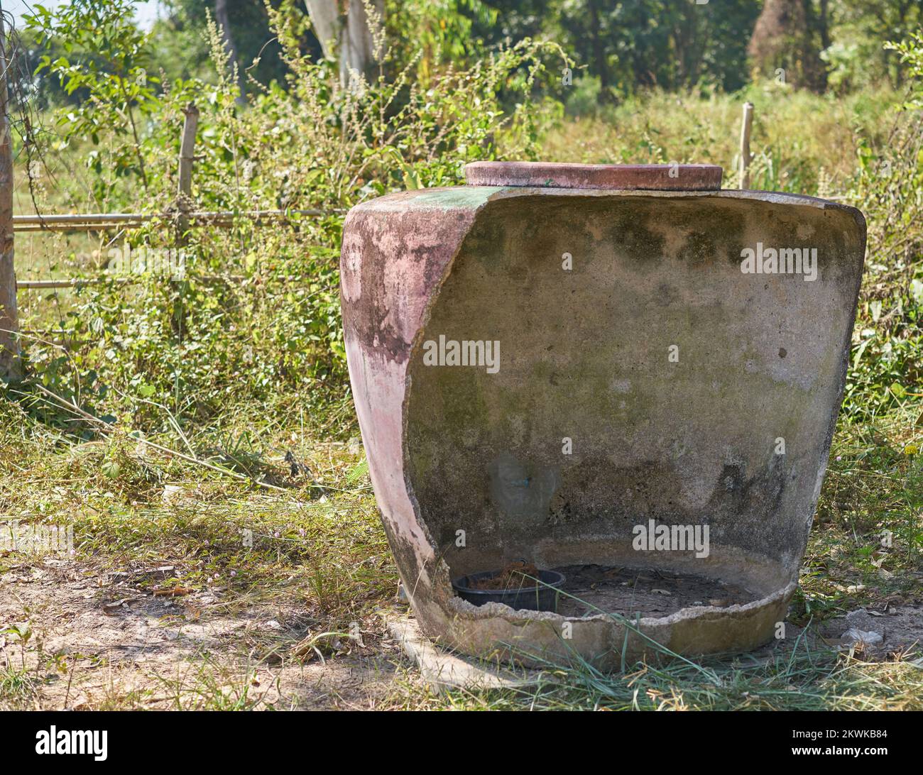 Ein großer traditioneller beschädigter Wasserbehälter auf einer Farm im ländlichen Thailand. Stockfoto
