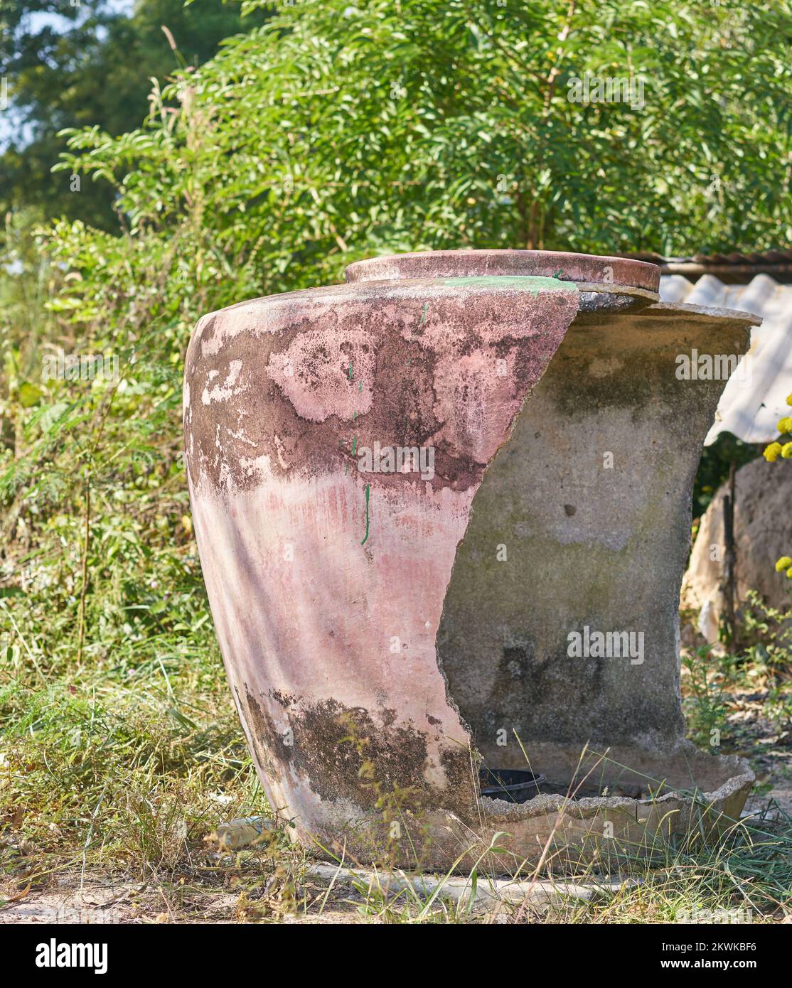 Ein großer traditioneller beschädigter Wasserbehälter auf einer Farm im ländlichen Thailand. Stockfoto
