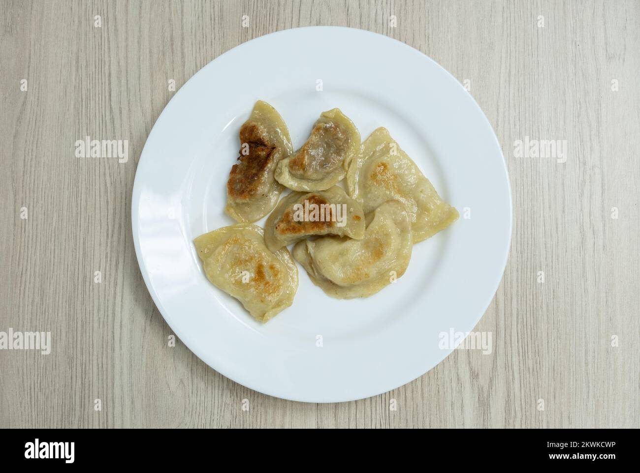 Gebratene Teigtaschen mit Kohl, Käse und Kartoffeln auf einem weißen Teller mit Schmalz. Die Haut ist braun und braun. Stockfoto