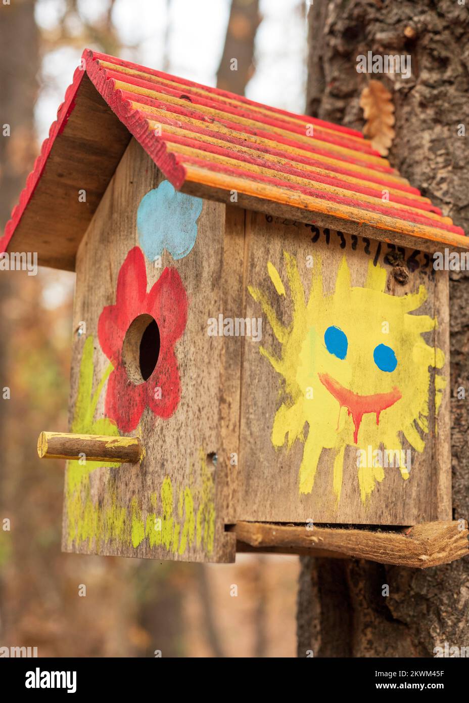 Lustiges, farbenfrohes, handbemaltetes Vogelhaus auf einem Baum Stockfoto