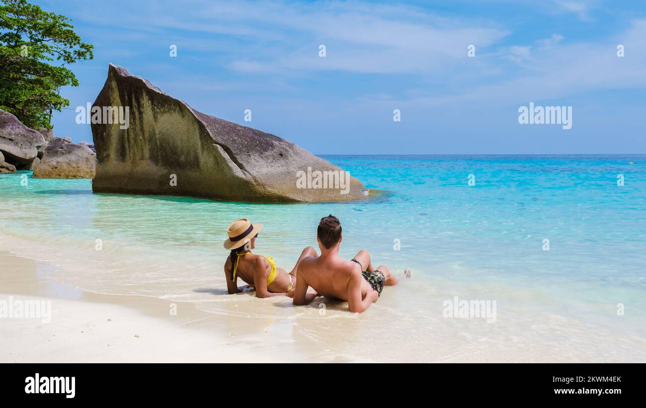 Ein paar Männer und Frauen sitzen am tropischen weißen Strand mit türkisfarbenem Ozean der Similan Inseln Thailand. Stockfoto