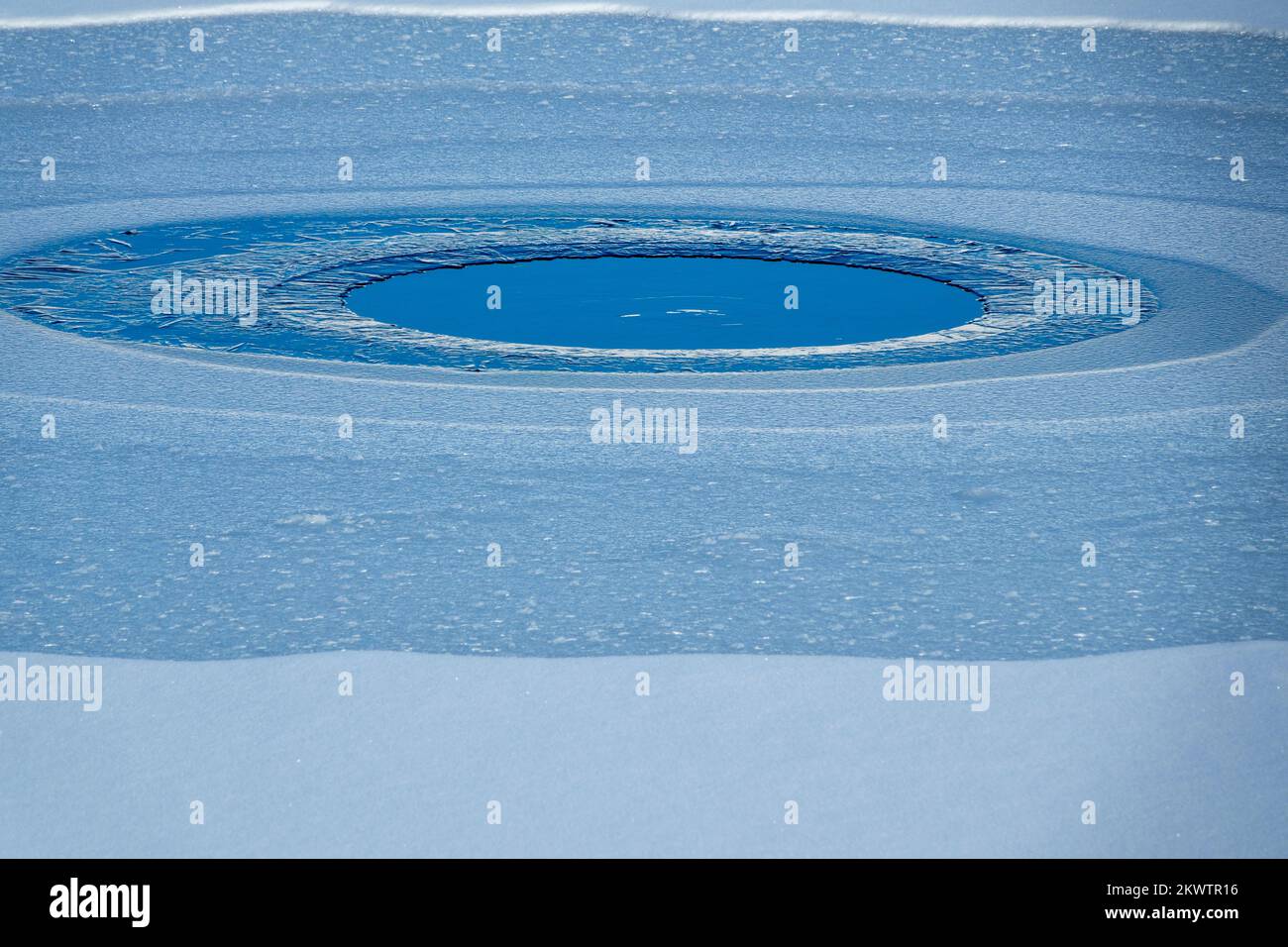 Kleiner gefrorener See in Winterbergen. Es schneit Stockfoto