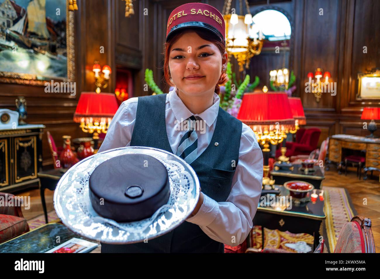 Eine Kellnerin des Hotel Sacher zeigt eine köstliche Sachertorte in der Lobby des Hotel Sacher Vienna Austria. Das Hotel Sacher ist ein 5-Sterne-Luxushotel Stockfoto