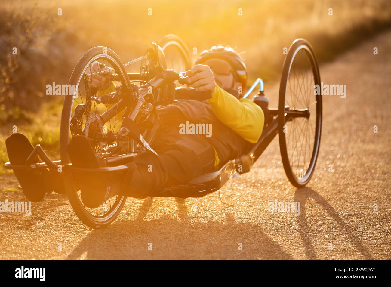 Malerische Aufnahme eines jungen Sportlers mit Behinderung auf einem Handrad. Adaptives Training bei Sonnenuntergang im Freien. Hochwertige Fotografie. Stockfoto