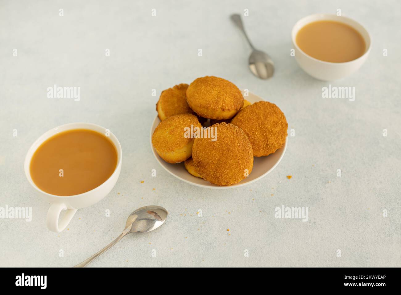 Köstlicher Snack: Zwei Tassen schwarzen Tee mit Milch und ein Plätzchen auf grauem Hintergrund. Stockfoto