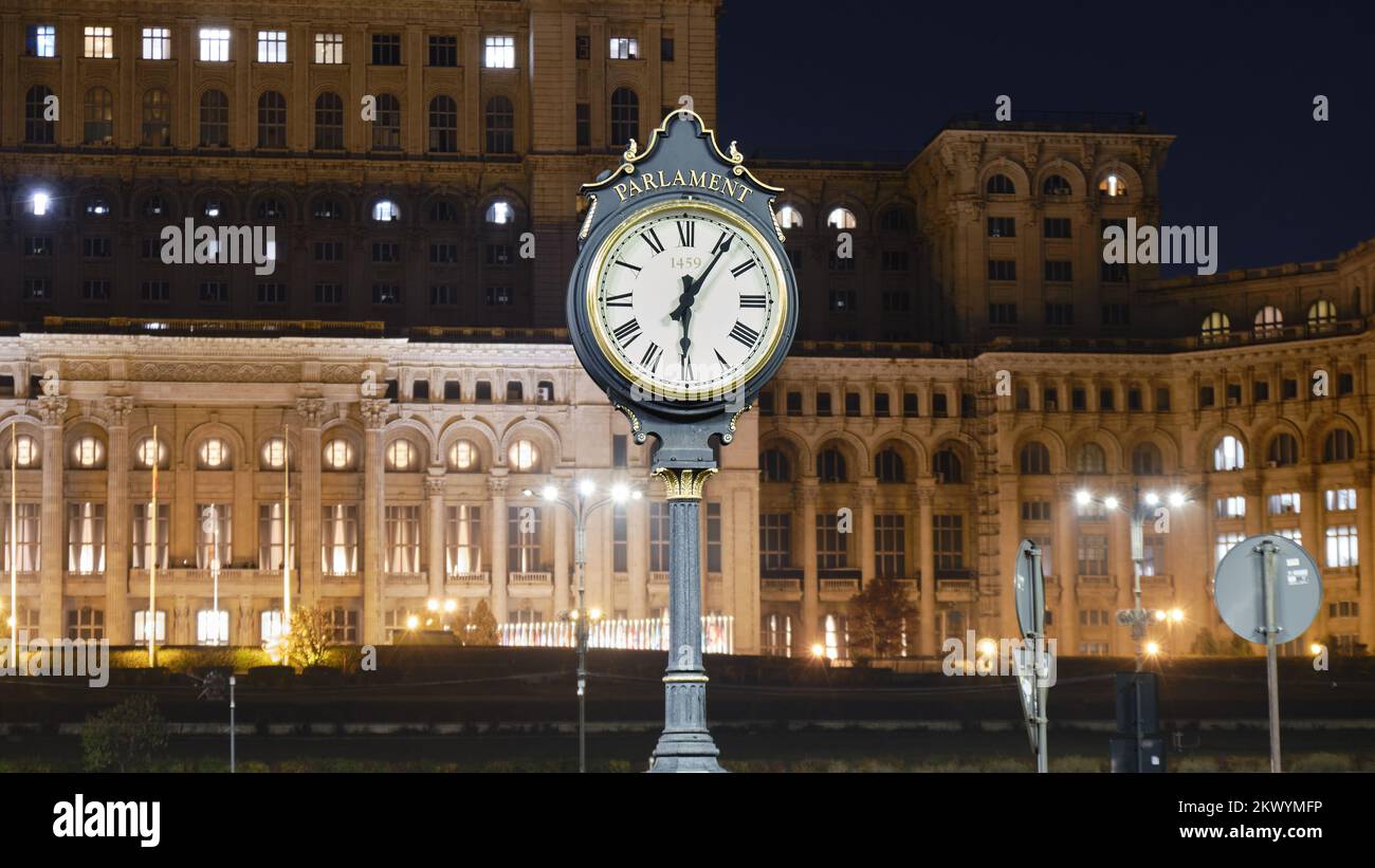 Öffentliche Uhr im Parlamentspalast in Bukarest, Rumänien, teilweise beleuchtet bei Nacht, um Energiekosten zu senken. Stockfoto