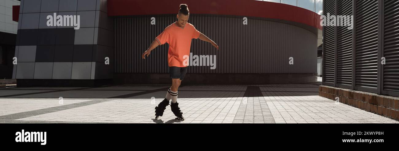 Junger Mann in Shorts und T-Shirt Rollschuhlaufen tagsüber auf der Straße, Banner, Stock Image Stockfoto