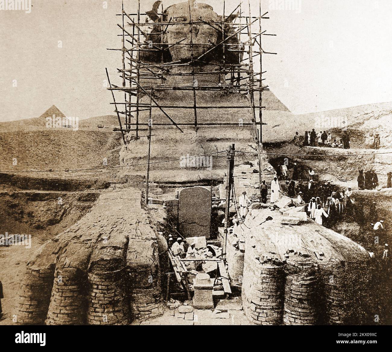 1940er Jahre – Ingenieure errichten Gerüste für Konservierungsarbeiten an der Sphinx, Ägypten. Technisch bekannt als Androsphinx (mit einem männerkopf). Es ist die größte und bekannteste Sphinx und wird oft als große Sphinx von Gizeh bezeichnet, wie sie neben der Großen Pyramide und anderen auf dem Gizeh-Plateau steht. Die Mammutstatue stellt eine Figur mit Löwenkörper und Pharaokopf dar und wird von einigen als Vertreter des pharaos Khufu alias Cheops (2589–2566 v. Chr.) angesehen. Aber das ist umstritten .. Andere glauben, dass der Kopf aus dem eines Löwen in der antiken Geschichte neu geschnitzt wurde. Ein Tempel steht zwischen seinen Beinen. Stockfoto