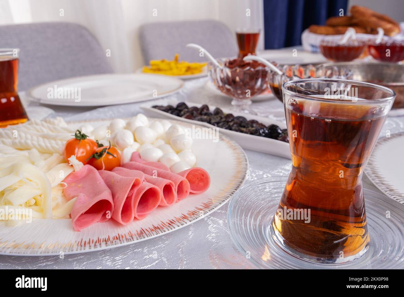 Türkischer Tee, Fotoglas mit frischem türkischem Tee aus der Nähe. Frühstückstisch. Sonntagsroutine für die Familie. Strick, Schnur und Käsekugeln mit Schinken im Teller. Stockfoto