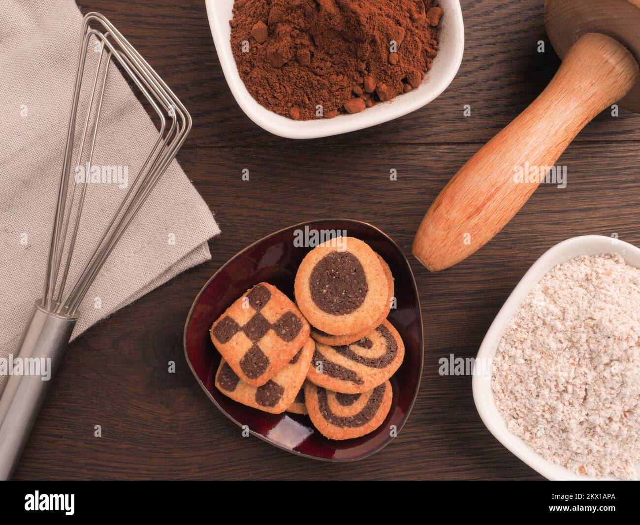 Schwarz-weiße Kekse auf einem hölzernen Küchentisch mit Backutensilien Stockfoto