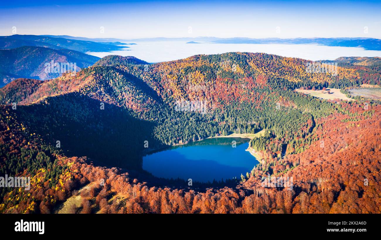 St. Ana Lake, Siebenbürgen, Rumänien. Atemberaubende Herbstlandschaft mit farbenfrohen Wäldern und idyllischem vulkanischen See, ein beliebtes Ziel für Touristen und Reisen Stockfoto