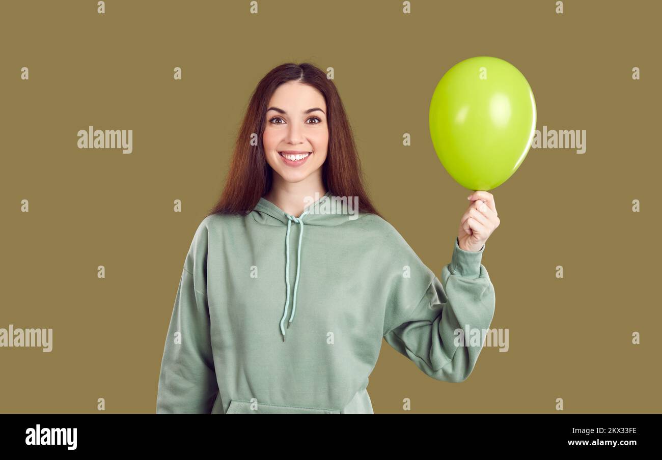 Porträt einer fröhlichen jungen Frau, die einen aufblasbaren Ballon auf Khaki-Hintergrund hält. Stockfoto