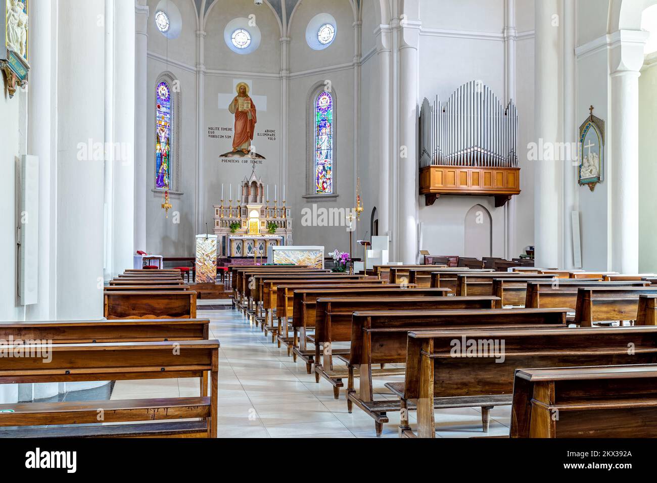 Blick auf Bänke, Altar und Orgel im Inneren von Divin Maestro - einer römisch-katholischen Pfarrkirche in Alba, Italien. Stockfoto