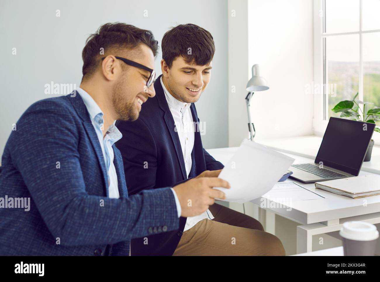 Zwei glückliche junge Geschäftsleute, die professionelle Papiere im Büro erledigen Stockfoto