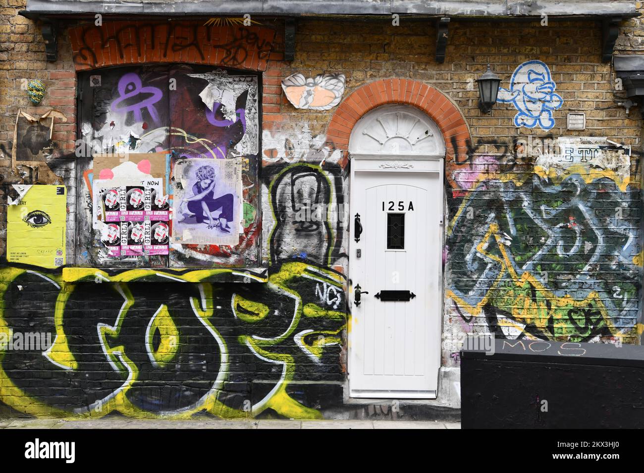 Weiße Haustür aus einer Wohnung umgeben von Graffiti in Shoreditch, London Stockfoto