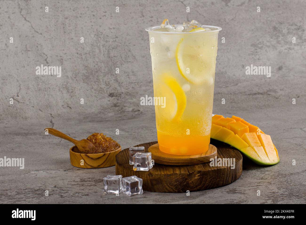 Boba- oder Tapiokapperlen ist taiwan Seifenmilchtee in Plastikbecher mit Mango-Zitronen-Aroma auf texturiertem Hintergrund, Sommererfrischung. Stockfoto