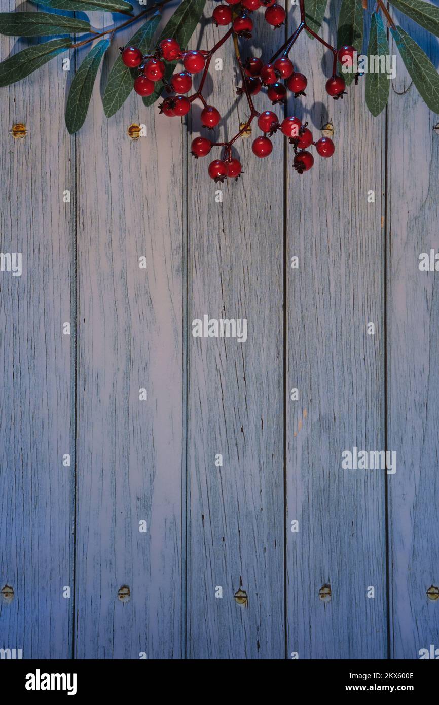 Rustikaler Hintergrund im Winter mit dekorativen Zweigen aus Rowan-Beeren mit grünen Blättern und roten Beeren. Flach liegend, Ansicht von oben, Platz für Text, Platz für Kopien Stockfoto